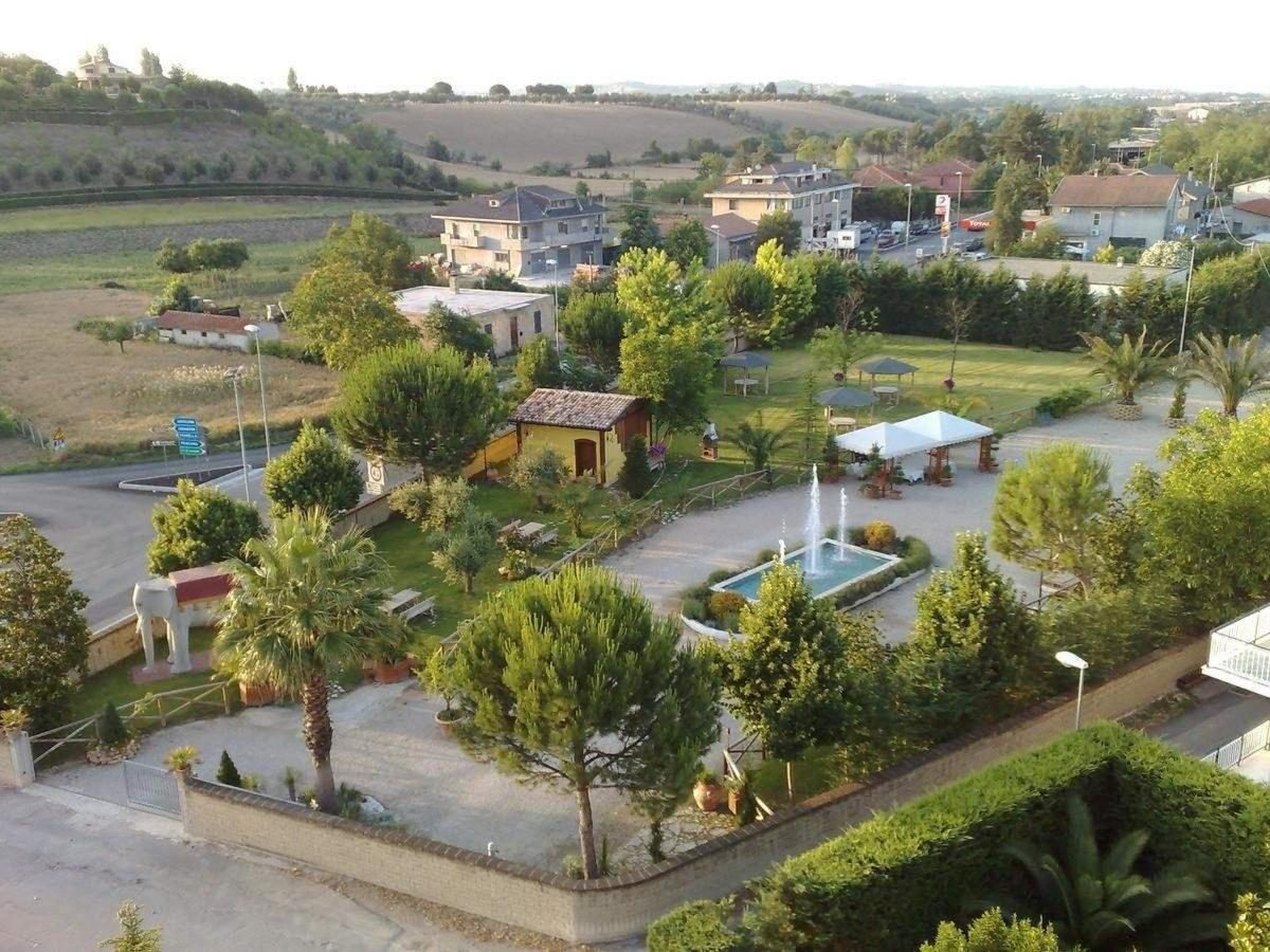 Giardino dell'hotel con tavoli all'aperto e ombra degli alberi